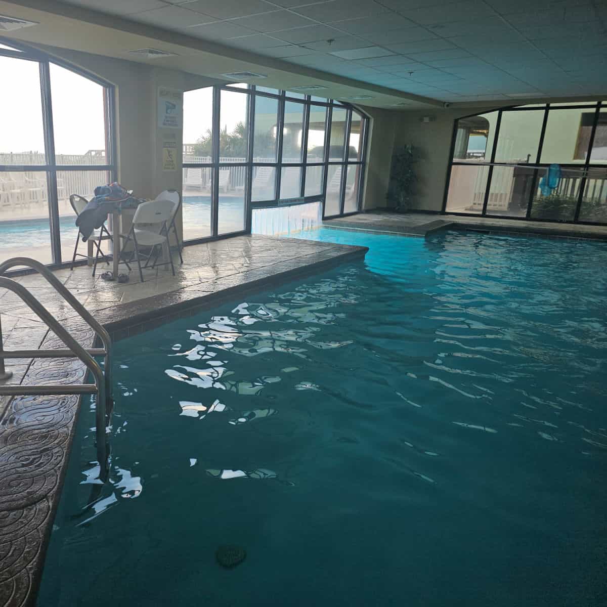 Indoor pool with swim through area to an outdoor pool, table and chairs on the pool deck