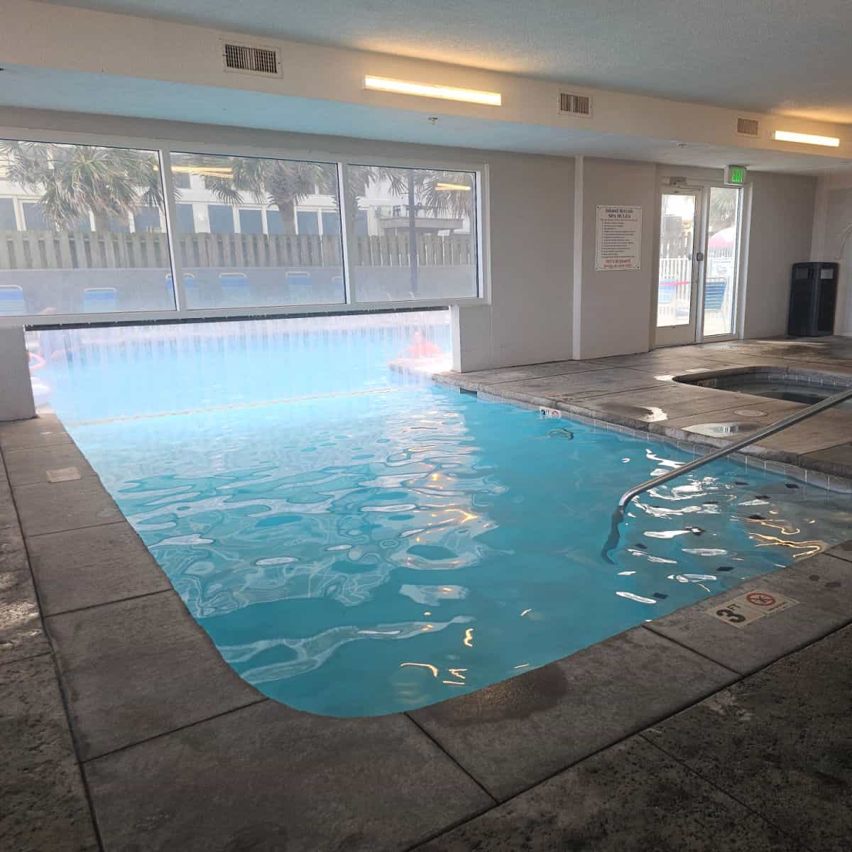 indoor pool with pool deck open to the outdoor pool