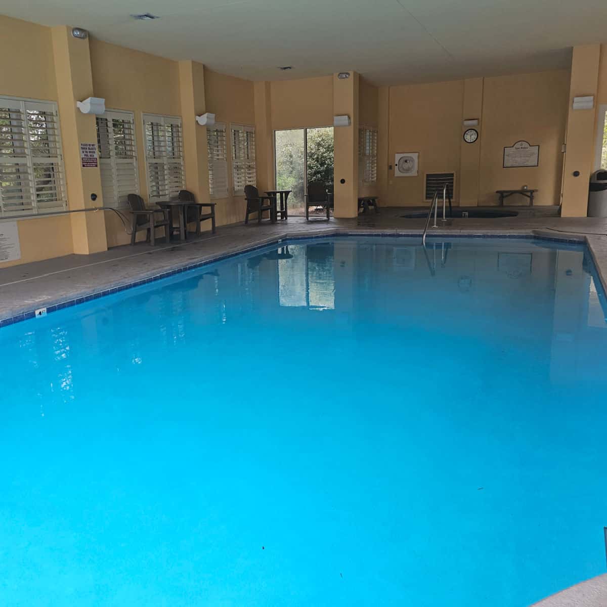 indoor pool with yellow walls, chairs around the walls