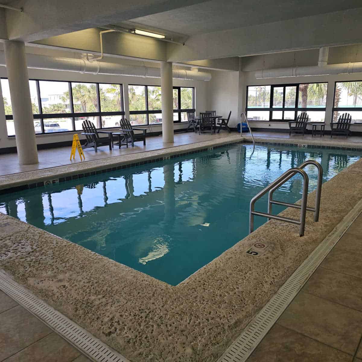 indoor pool with deck chairs around the pool, inside a building