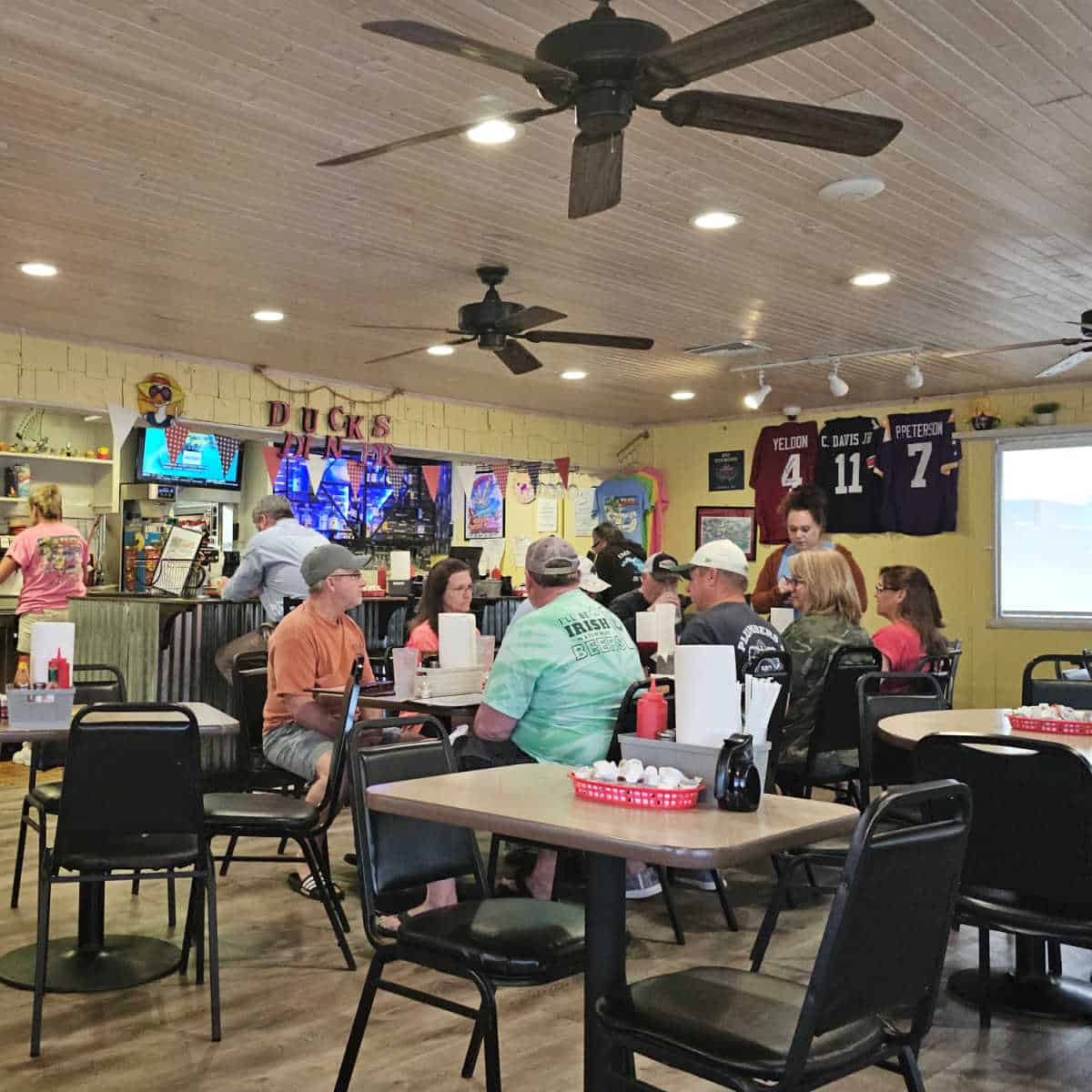 Duck's Diner indoor seatng with tables and chairs, football jerseys on the wall