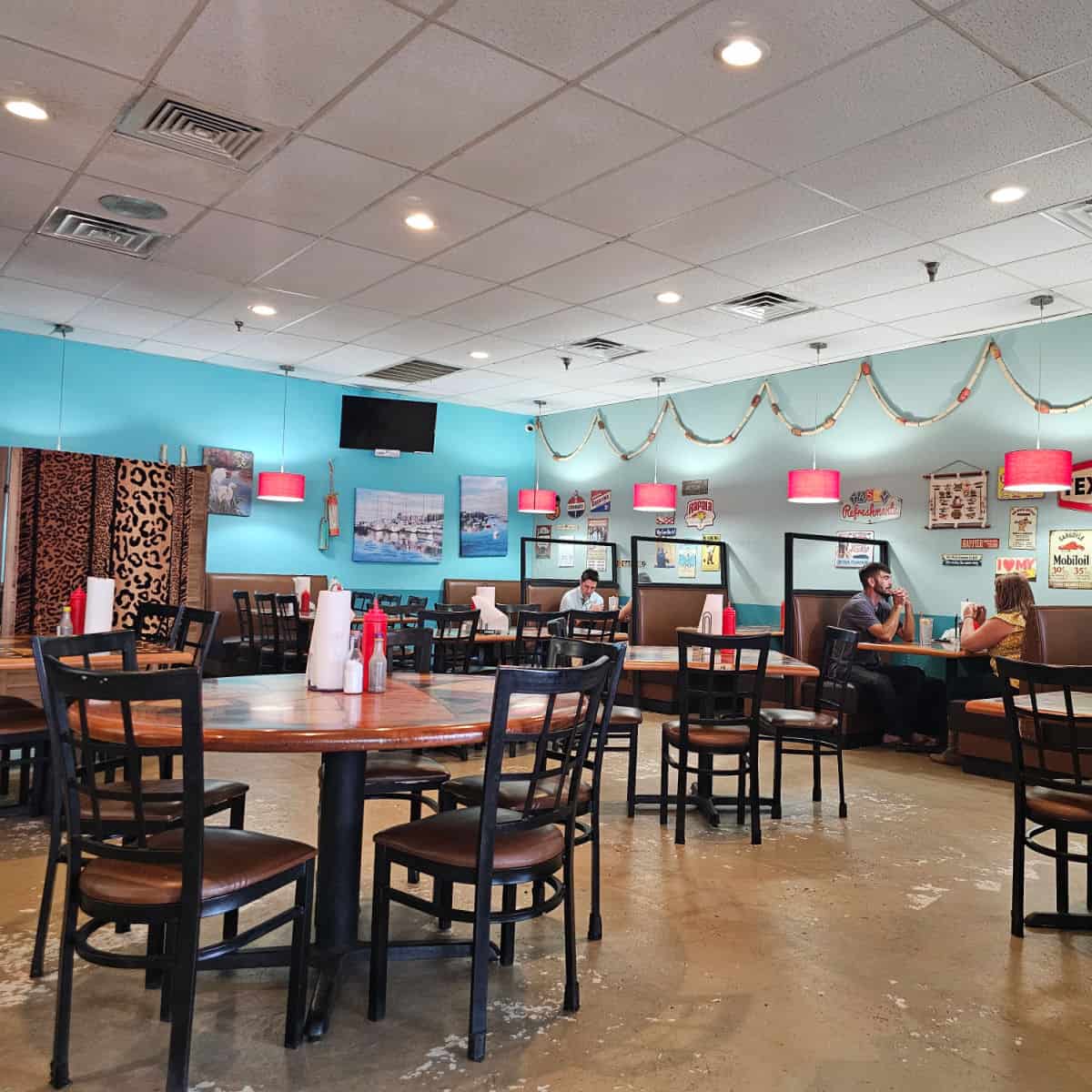 restaurant interior with booths along the wall, tables and chairs in the middle of the restaurant