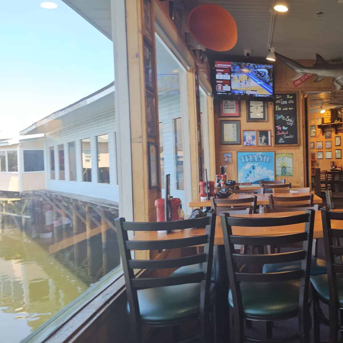 Indoor seating with tables and chairs next to a window overlooking the water