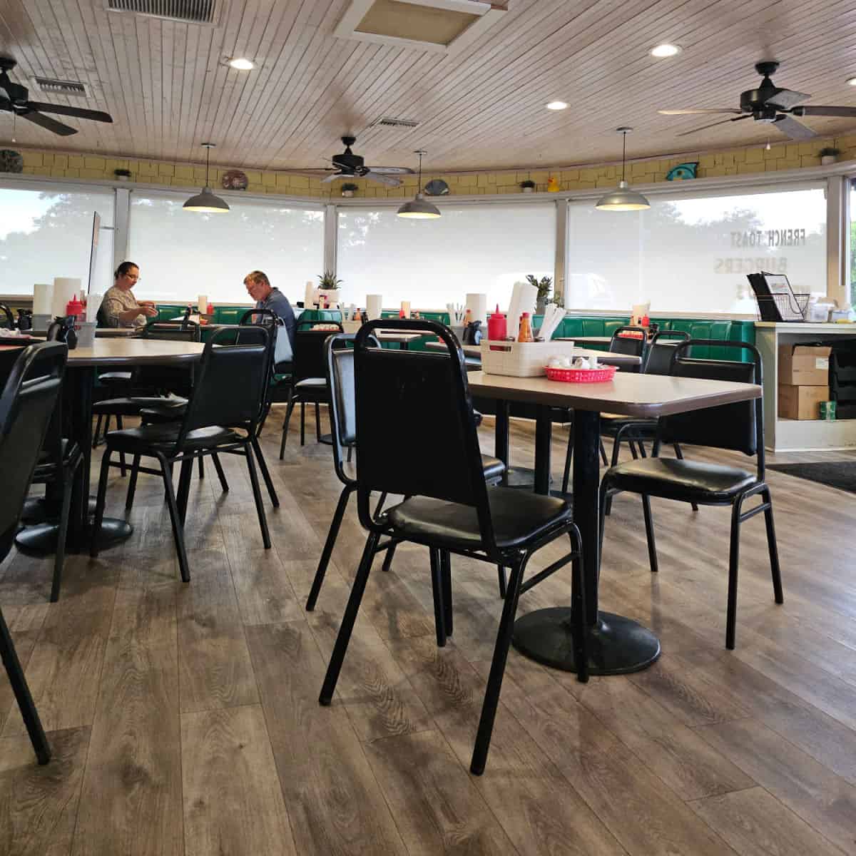 Ducks Diner indoor seating with tables and chairs, green leather booths around the edge of the restaurant
