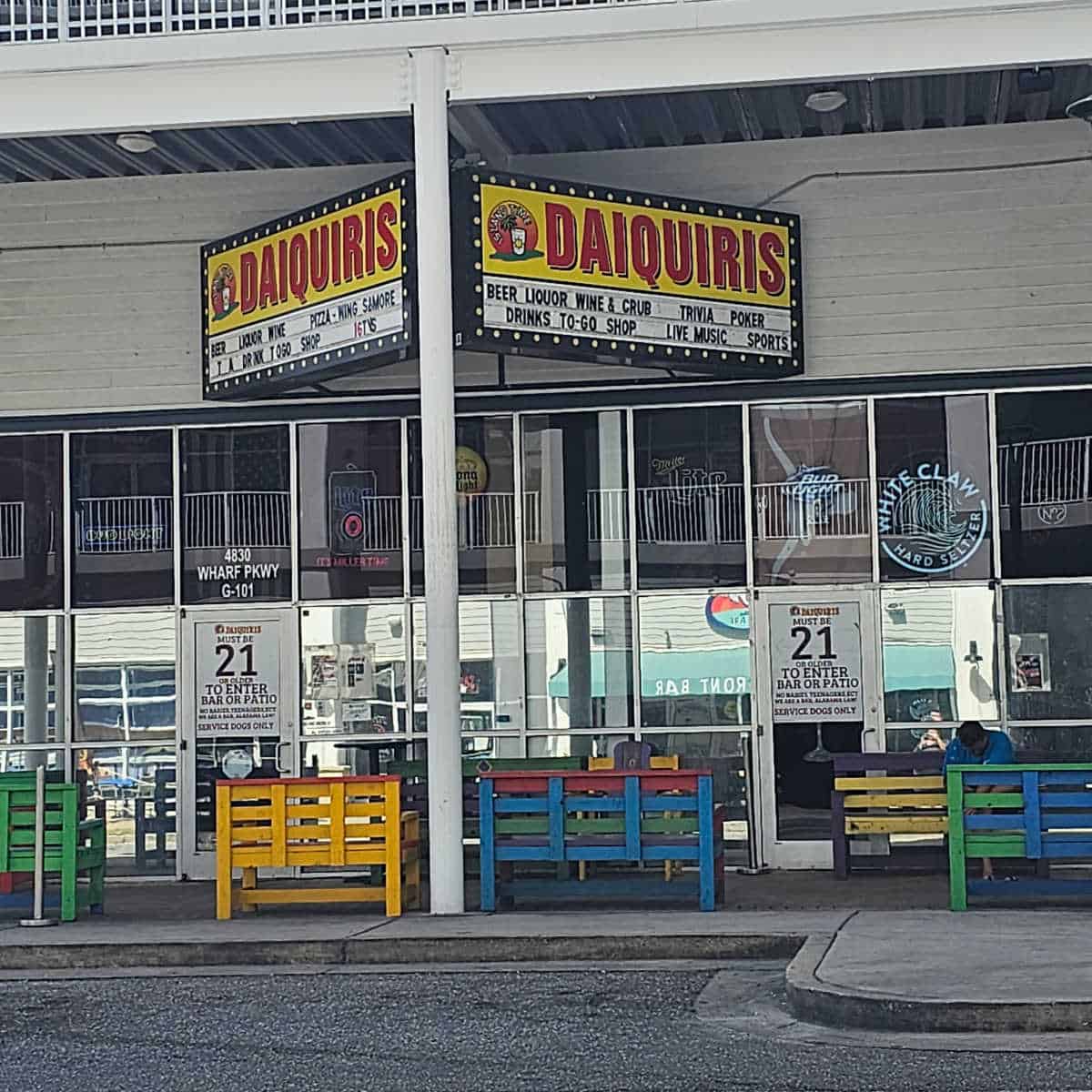 Island Time Daiquiris sign over the glass door entrance to the restaurant with colorful benches outside