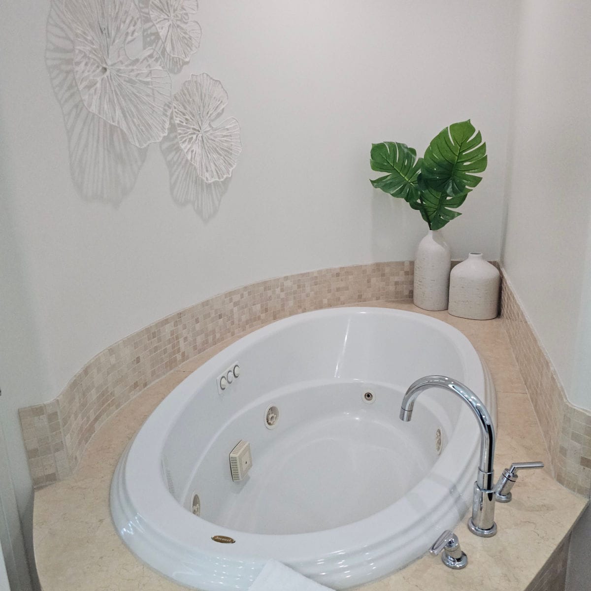 jaccuzi tub with greenery in a vase, white art on the all