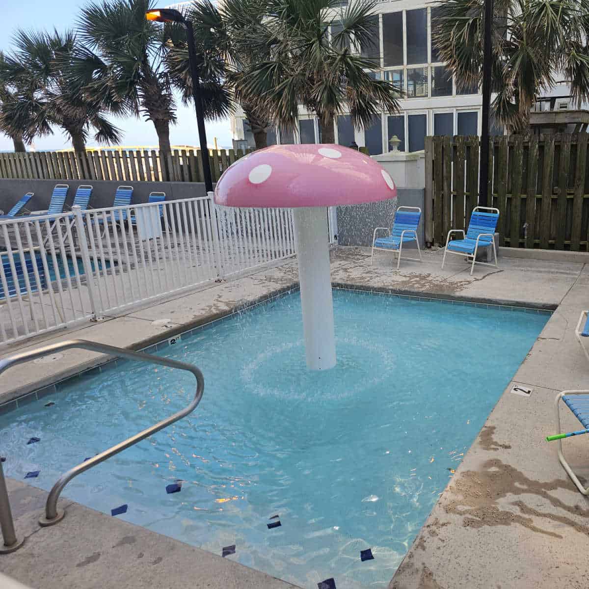 mushroom water feature in a kiddies pool chairs around the deck