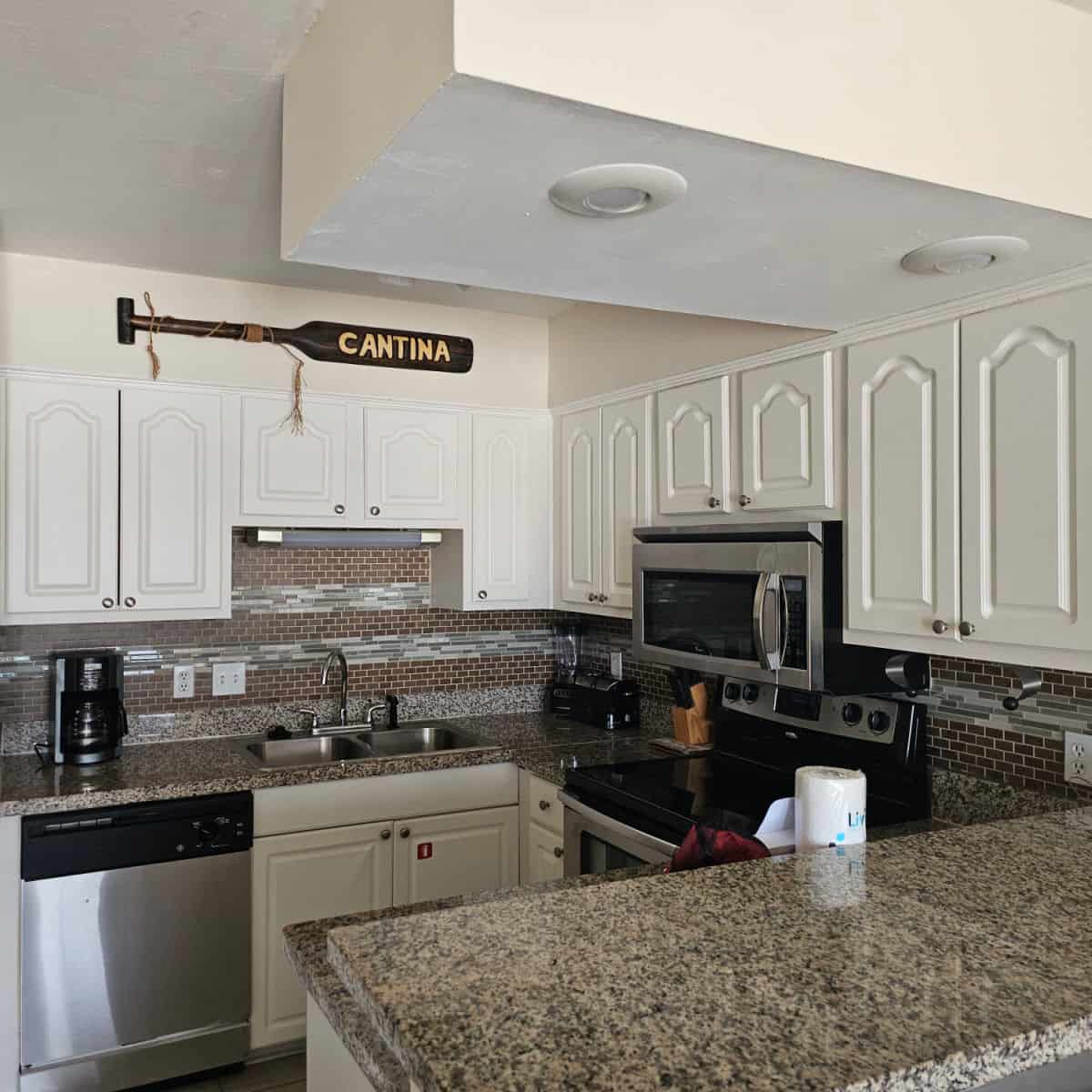 kitchen with an oar that says cantina over the kitchen cabinets, stainless steel appliances.