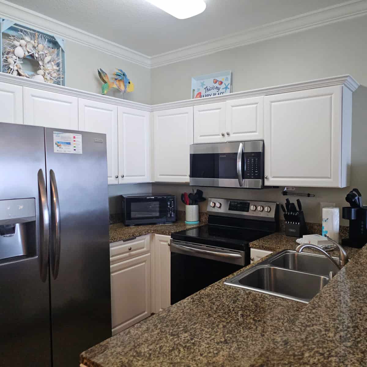 Kitchen with white cabinets, art on top of the cabinets