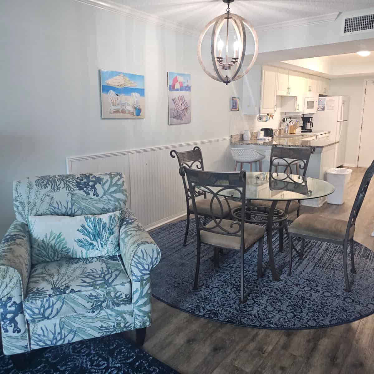 chair with coral design next to a small dining room table and kitchen in the background