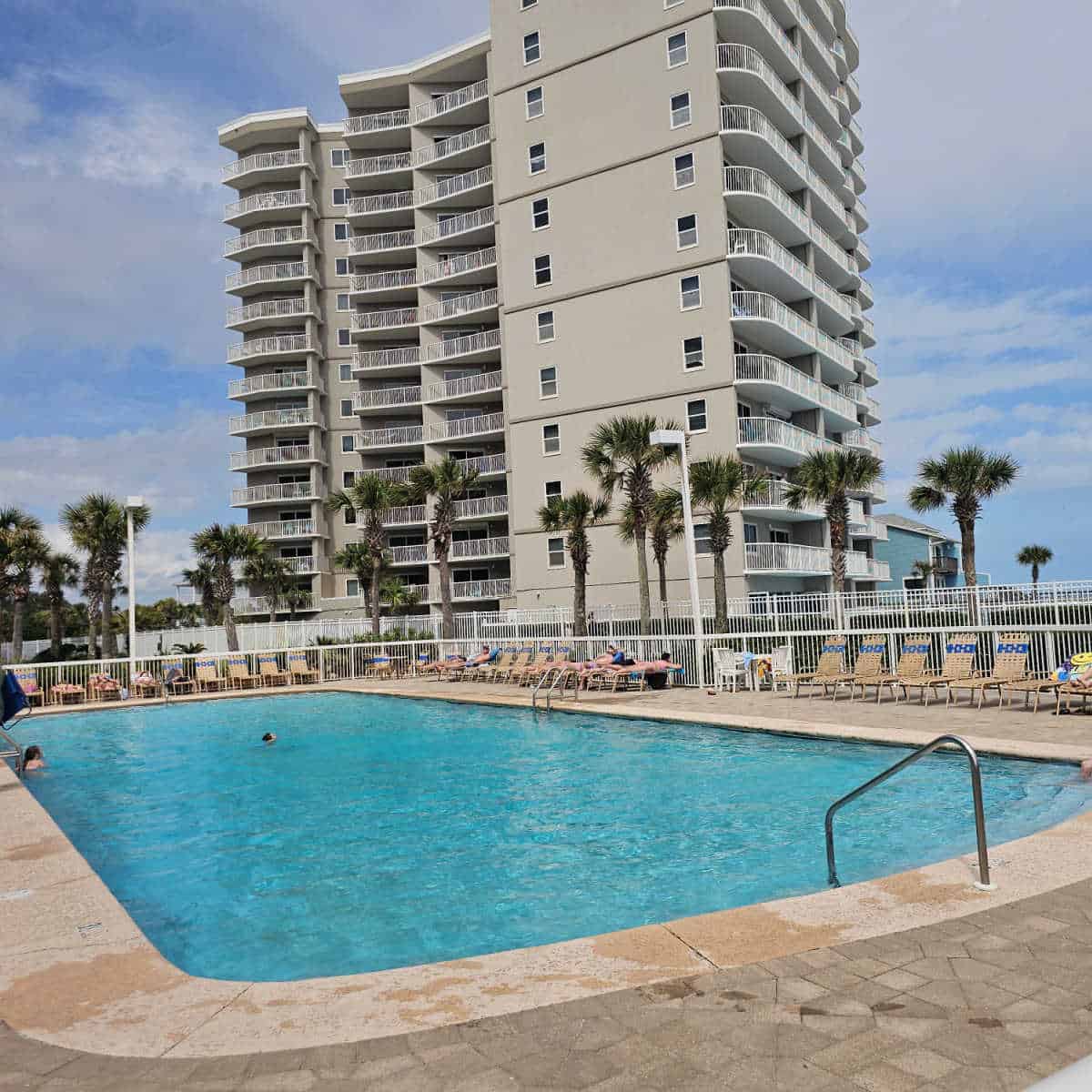 outdoor pool with pool chairs around the deck, tall building in the background