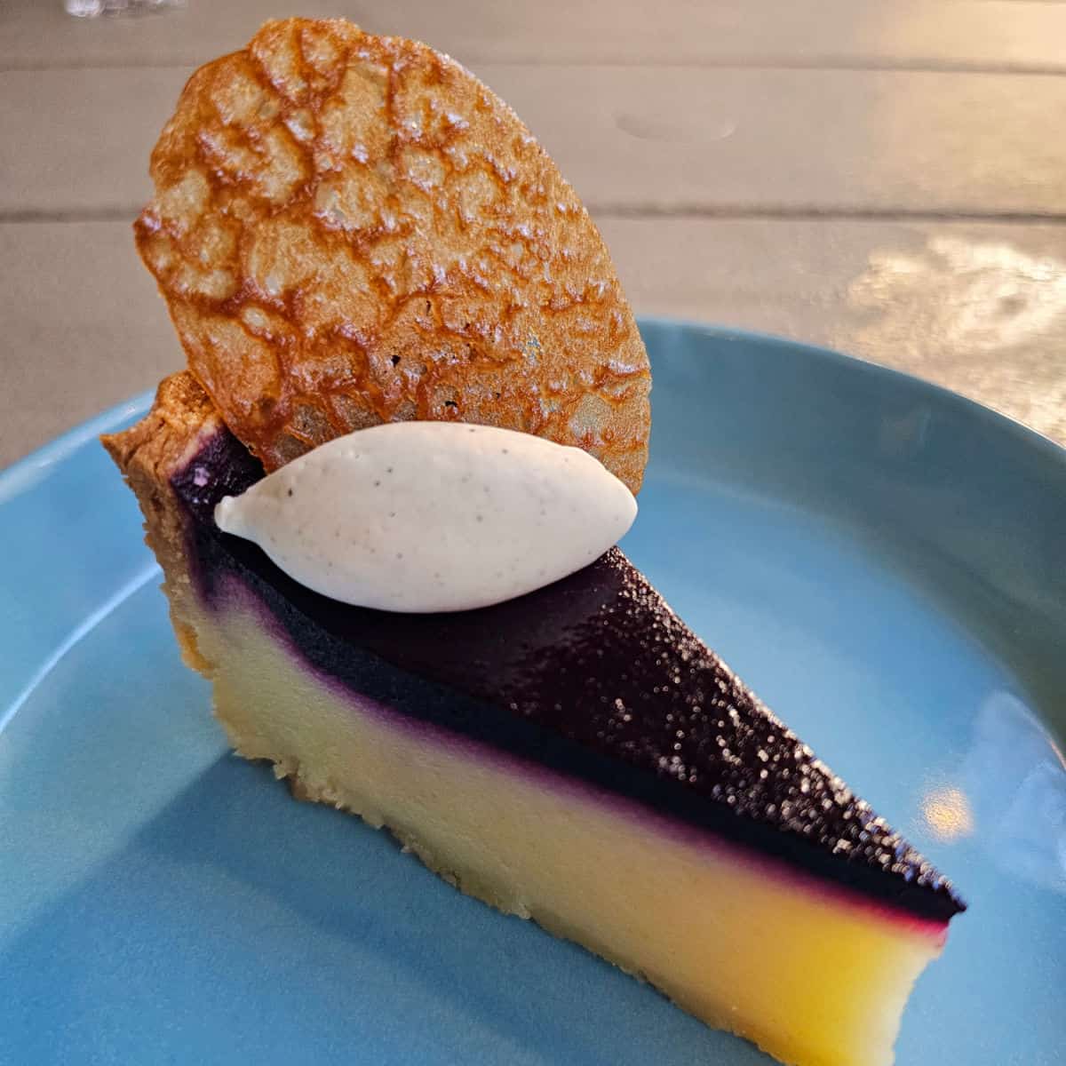 lemon pie with blueberry topping, cookie on top, sitting on a blue plate