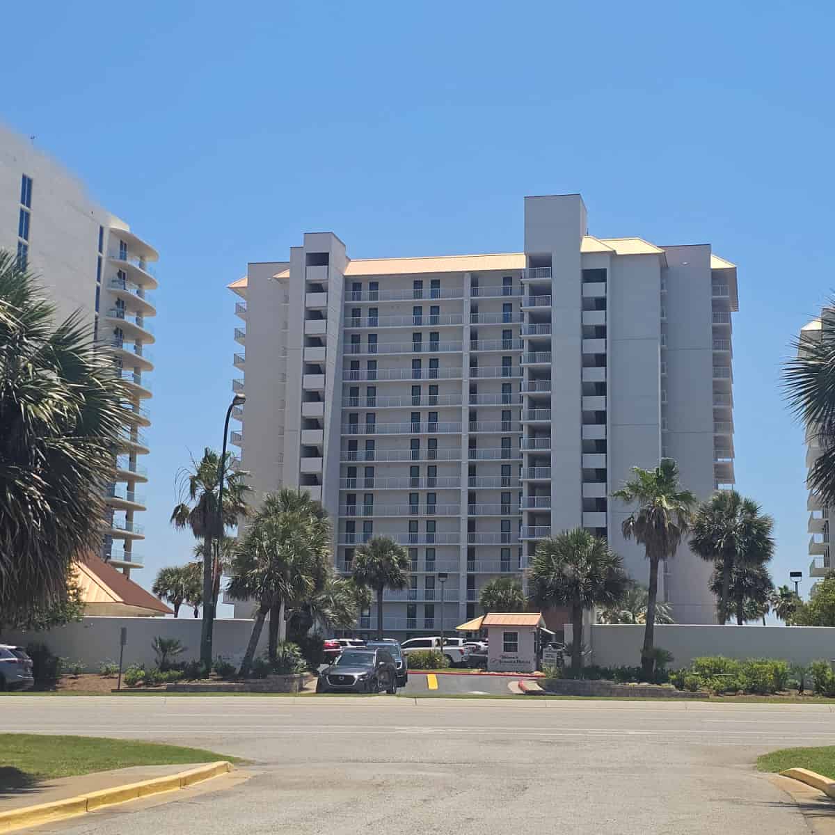looking across Perdido Beach blvd to a large white building and palm trees