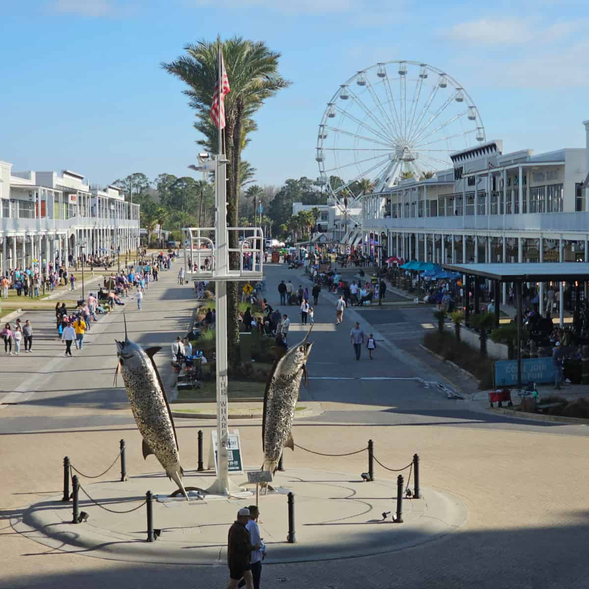 looking over Marlin Circle down the main street of The Wharf with palm trees down the middle, Wharf ferris wheel on the far right side