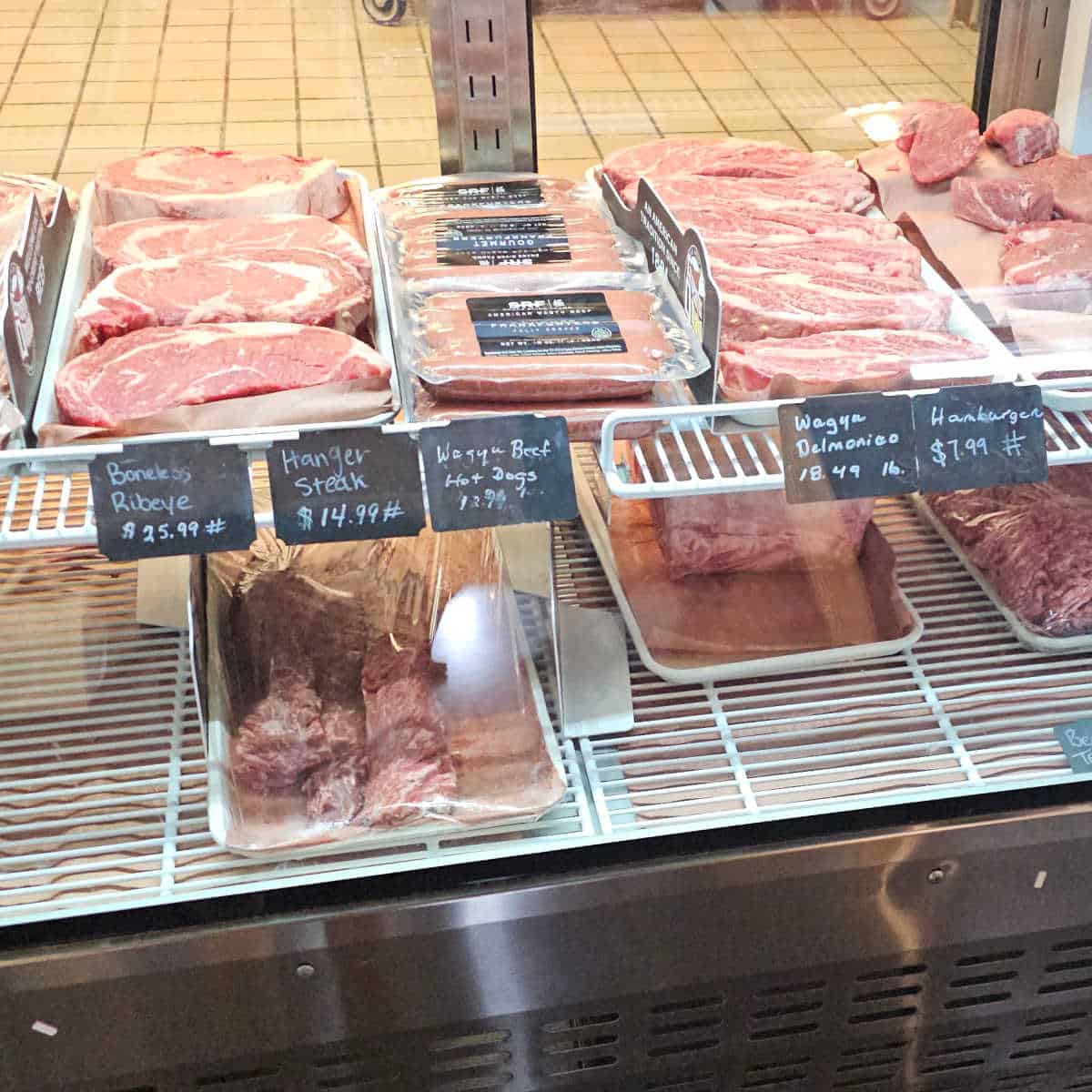 steaks and meat on trays in a refrigerator case