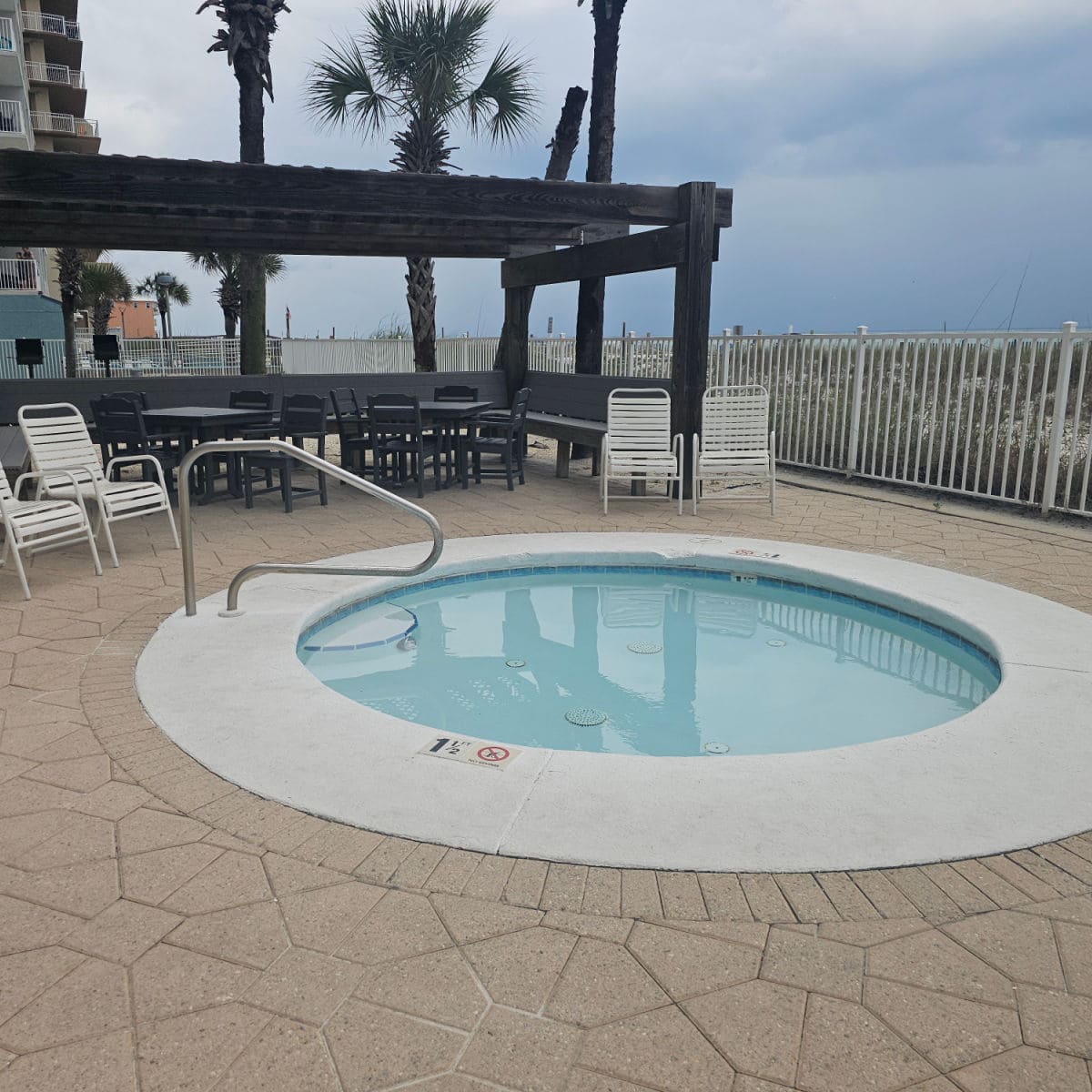 hot tub with chairs near it and a covered area.
