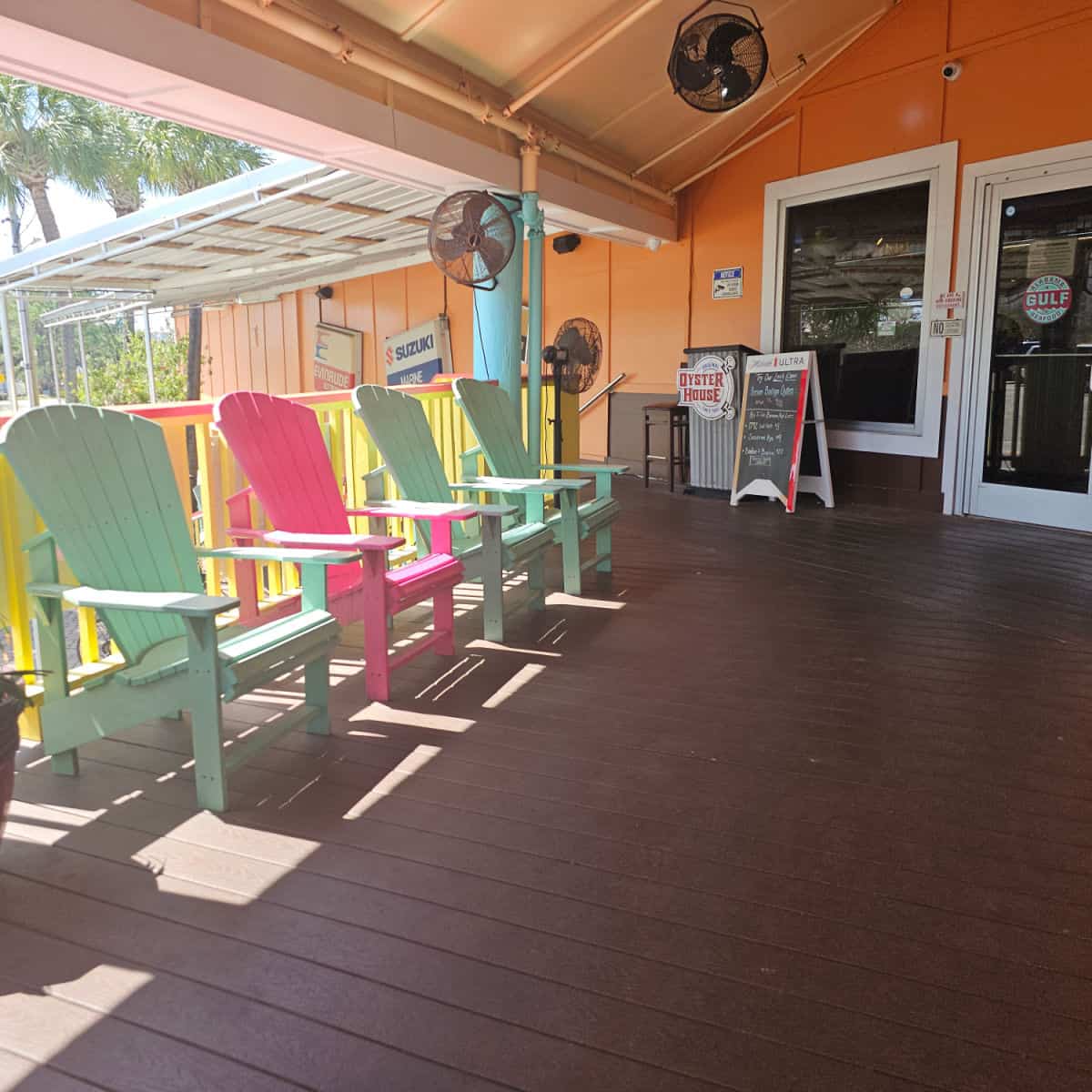 outdoor covered seating with brightly colored Adirondack Chairs near the front entrance to the Oyster House