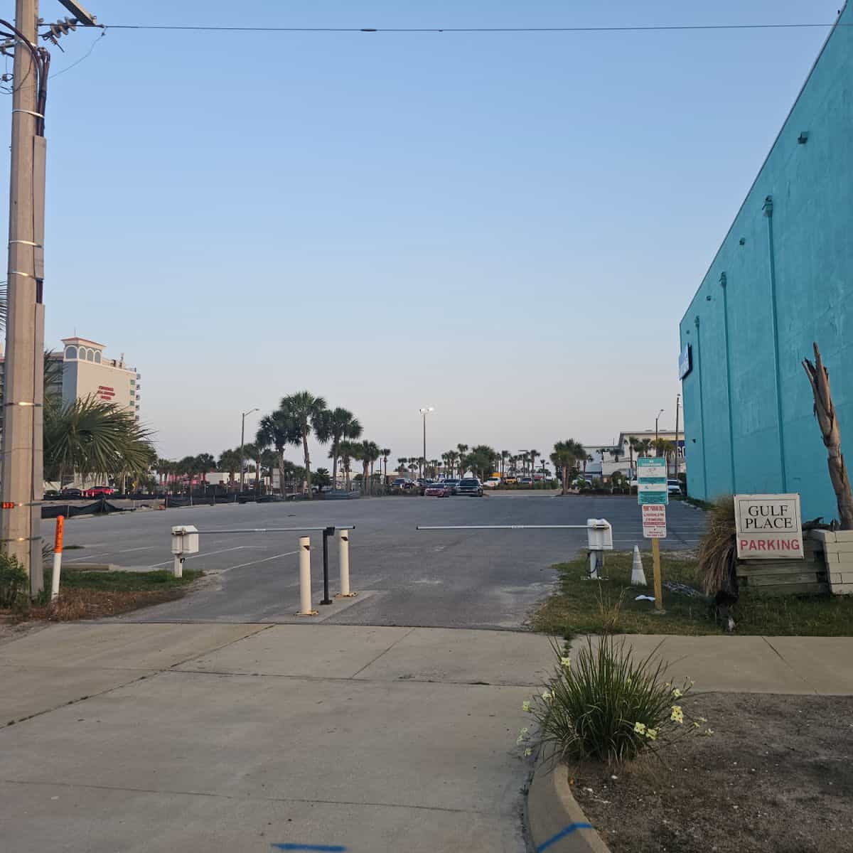 gulf place parking sign next to a entrance bar, turquoise building to the right