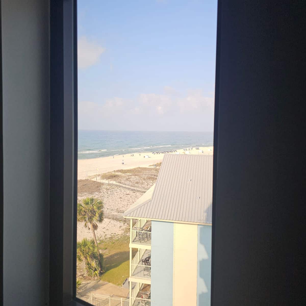 Looking out a window to the beach with the Gulf in the distance
