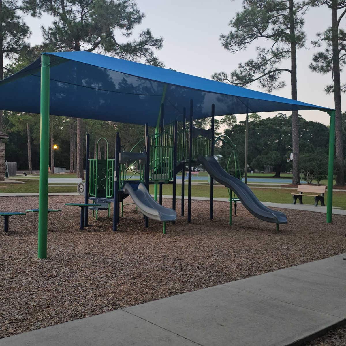 kids play area under a blue covering surrounded by trees