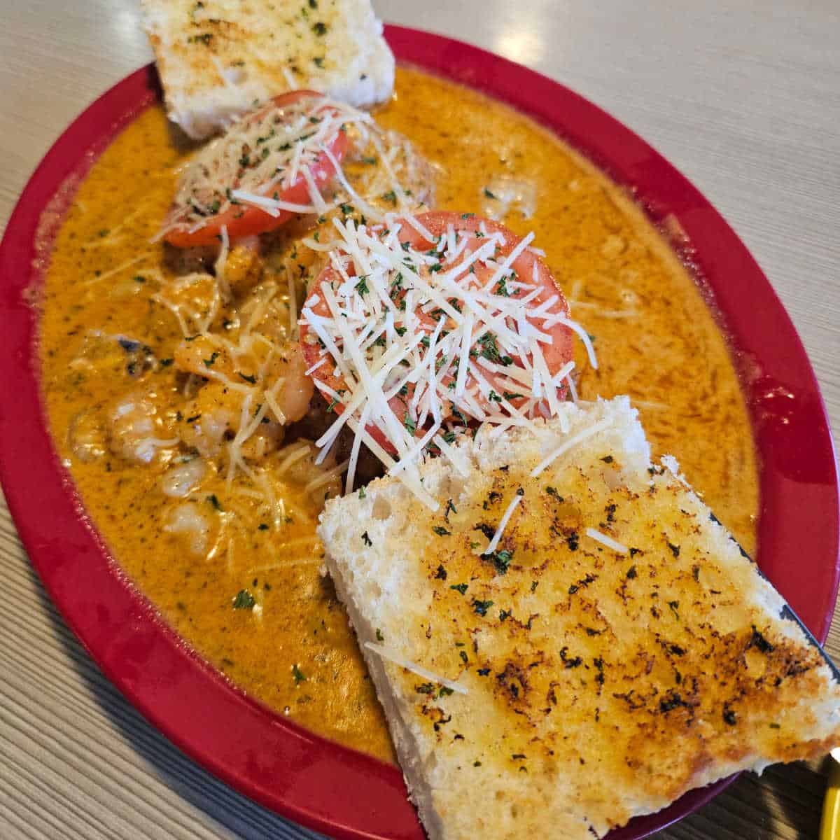 Shrimp and grit cakes with two pieces of bread on a red plate