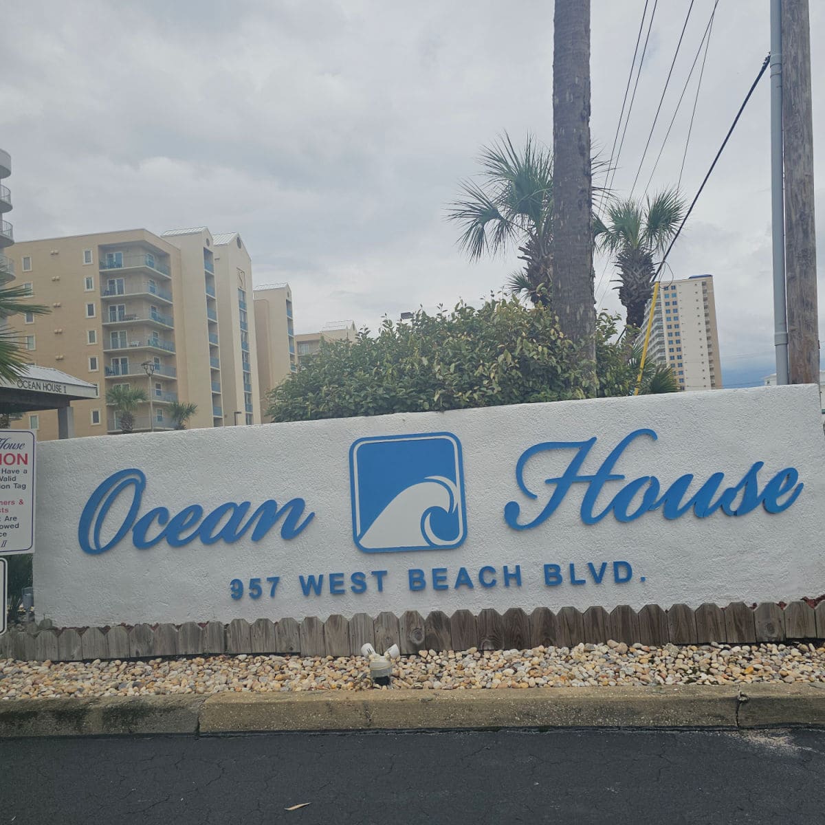 Ocean House sign with palm trees and buildings in the background