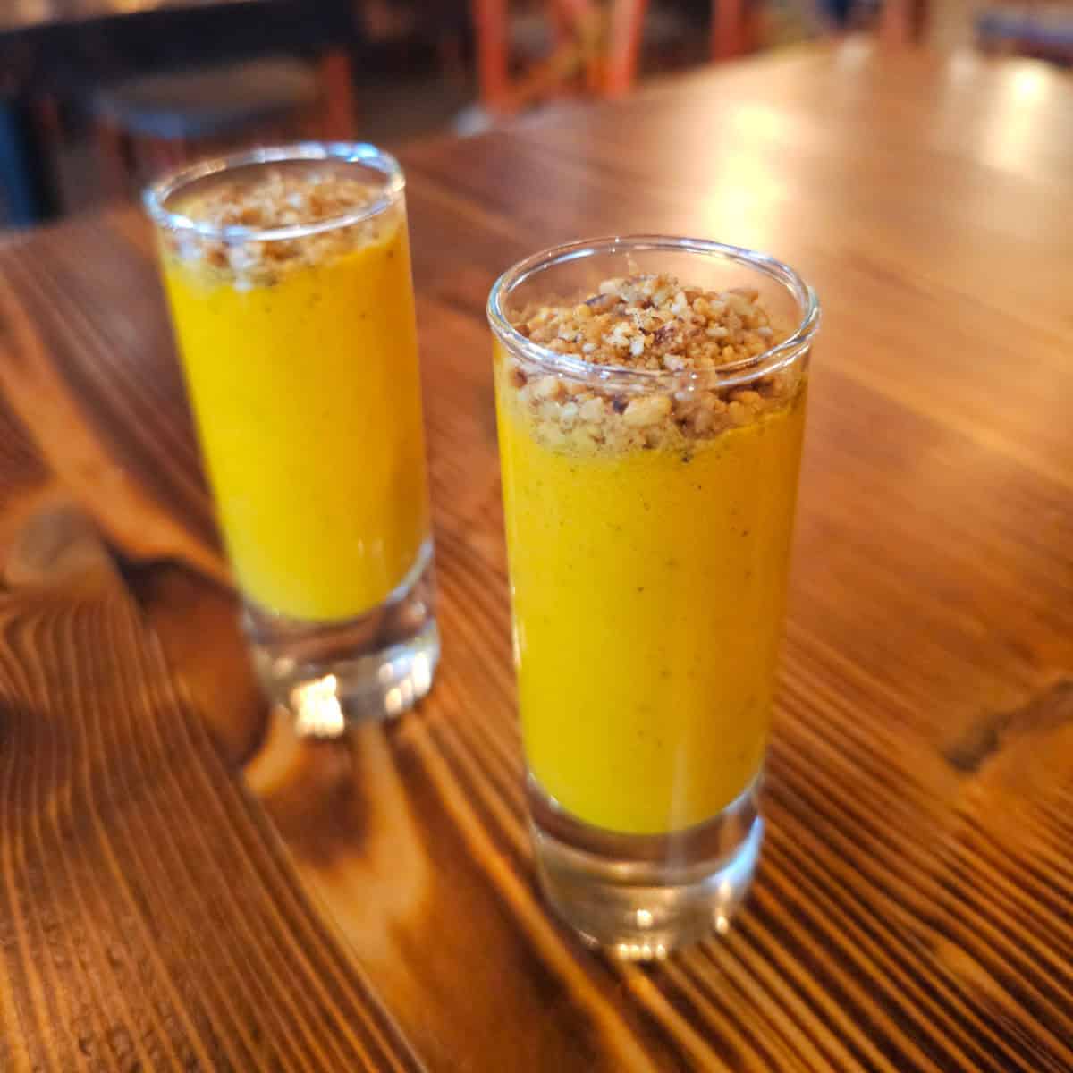 carrot sundown shots with nuts crumbled on top in two glasses