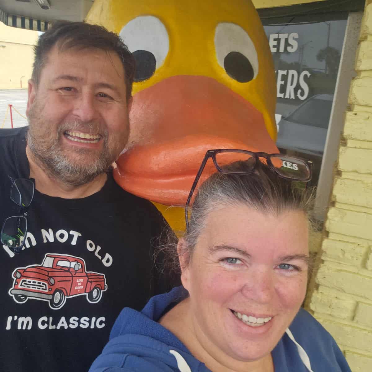 Tammilee and John standing next to a large yellow duck