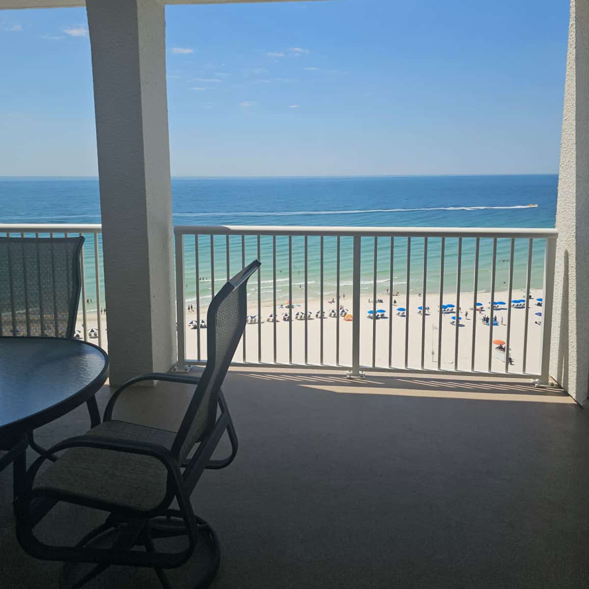 looking over a balcony with a table and chair to the white sand beach and Gulf waters
