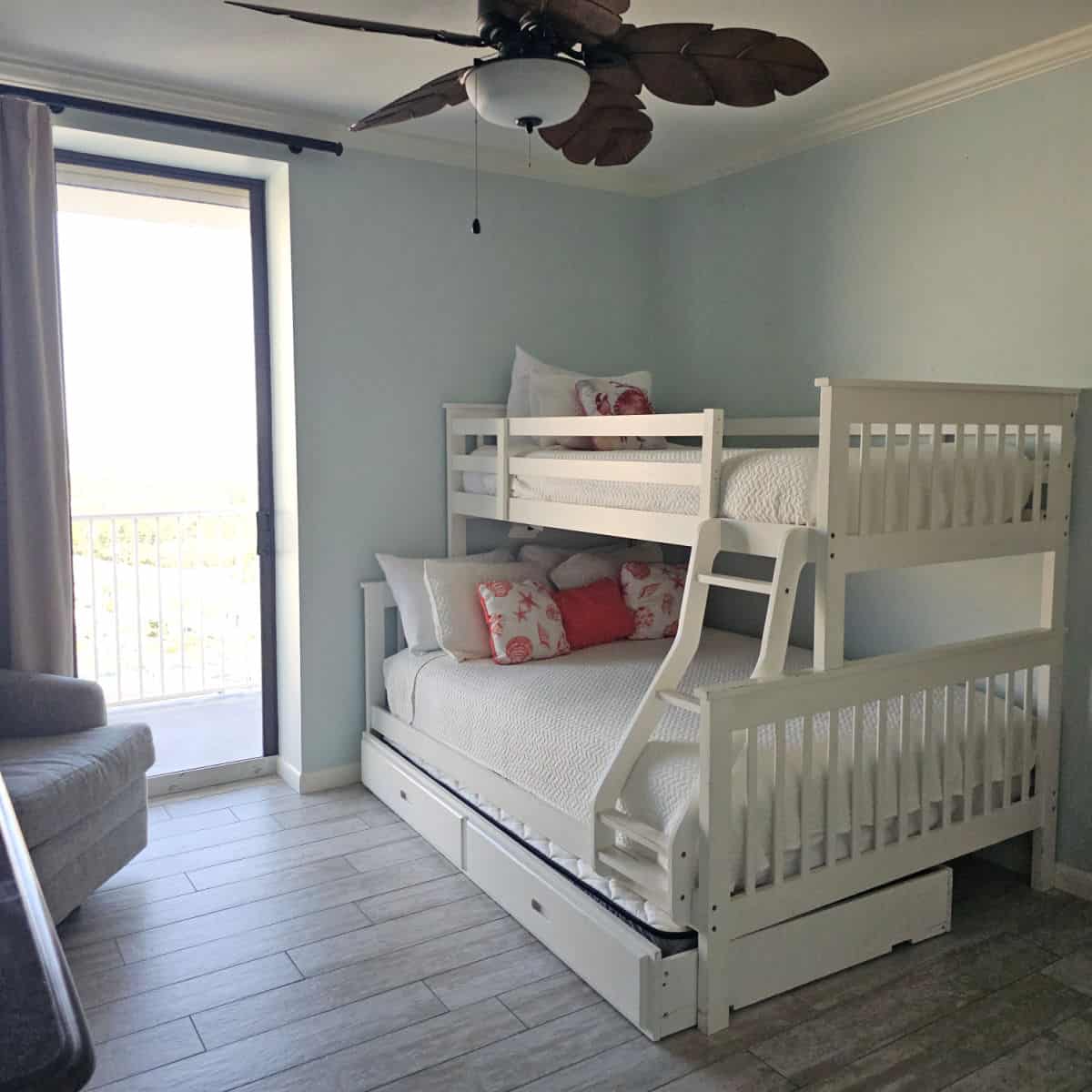 white bunkbed with a drawer under it, wooden leaves fan light, chair in the corner