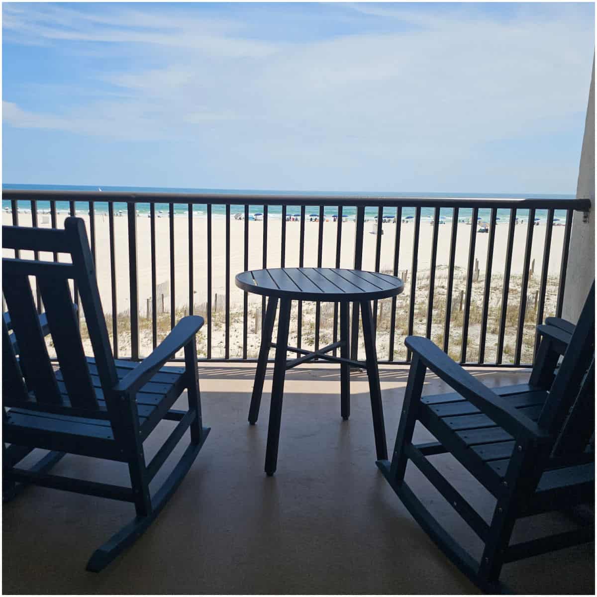 rocking chair and table on a balcony looking out to the beach