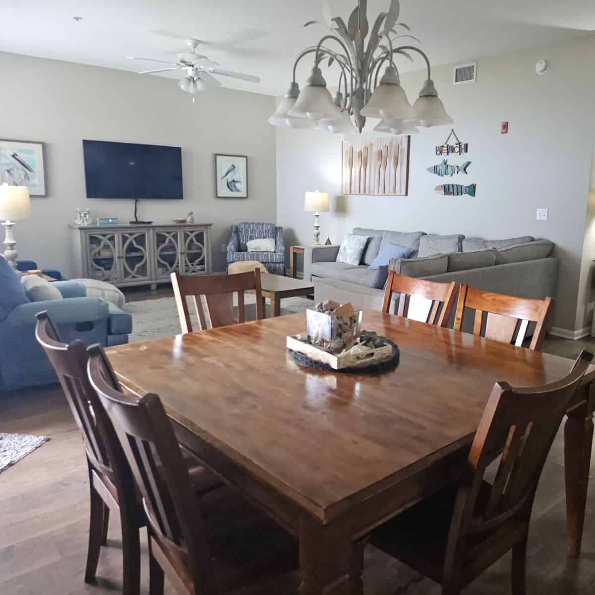dining room table with light over it with livng room in the background with sofa and chairs