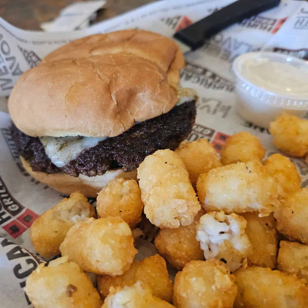 Veggie burger and tater tots in a Hurricane Grill & wings paper wrapped basket