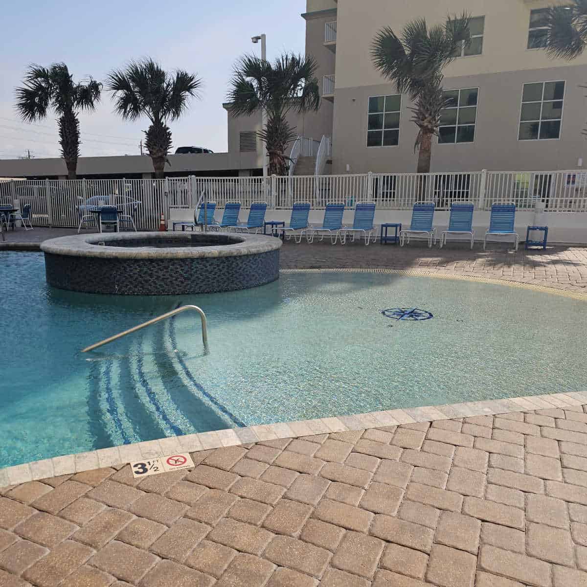 Zero entry pool with hot tub in the corner, building in the background