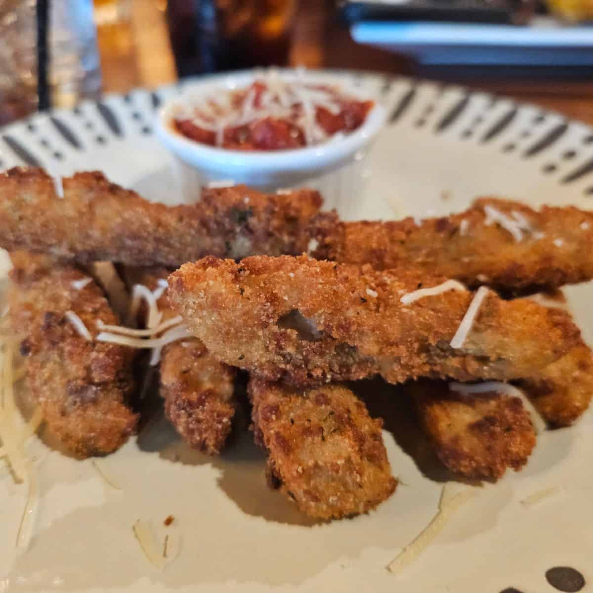 fried zuccini fingers on a white plate with marinara saue
