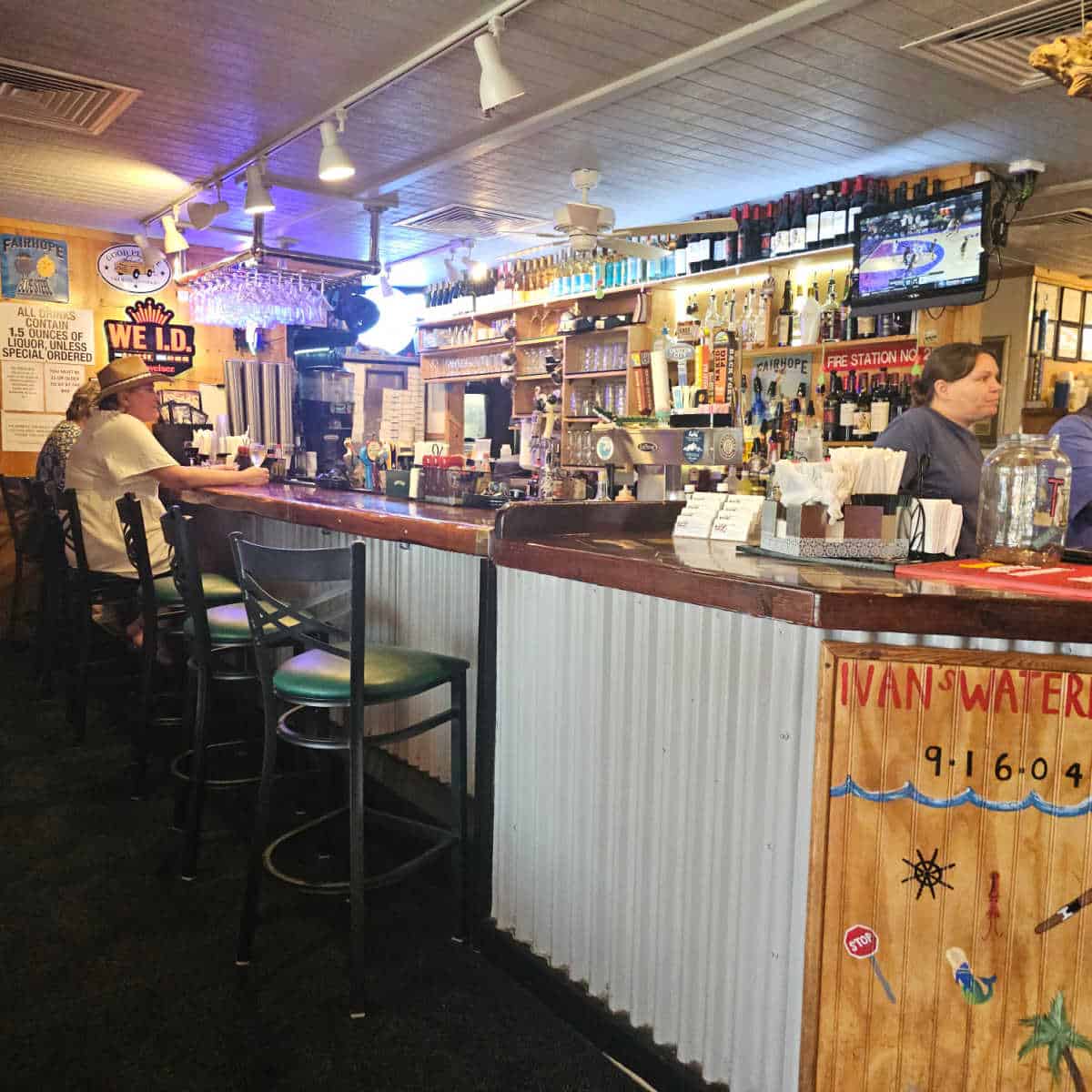 indoor bar with peoplesitting on tall chairs looking at a tv in the oyster house