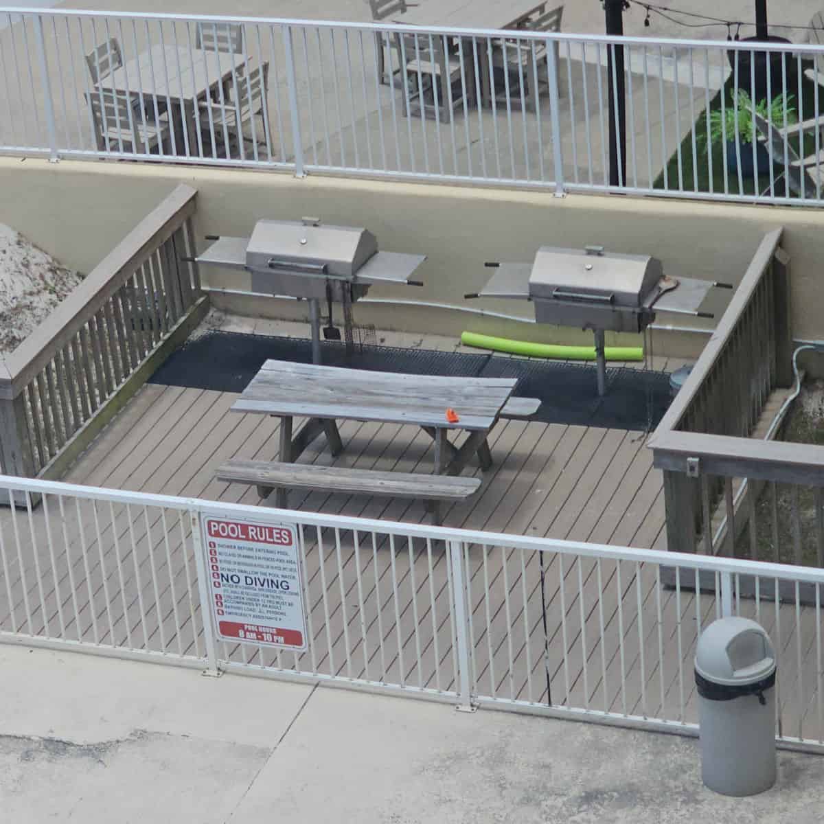 looking down over a fenced in barbecue area with a picnic table