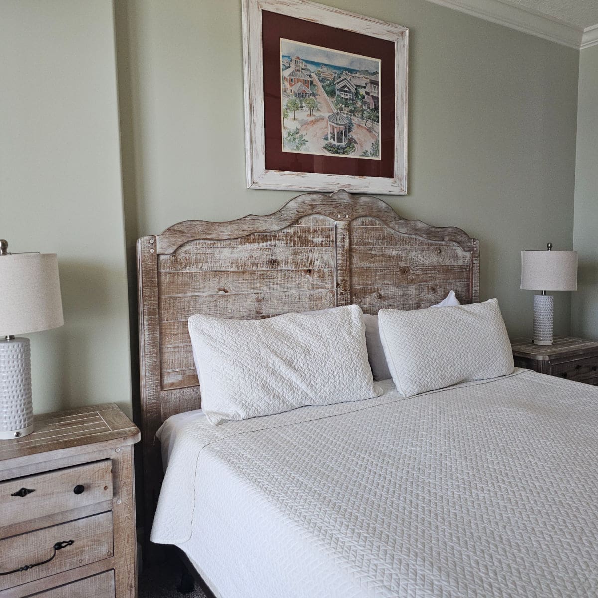 bedroom with wooden headboard over the bed with white linens, side tables with white lamps