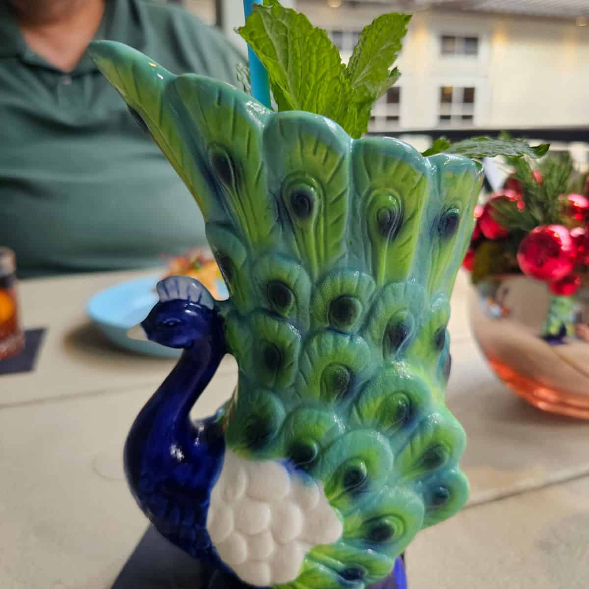 peacock shaped glass with a mint sprig coming out the top