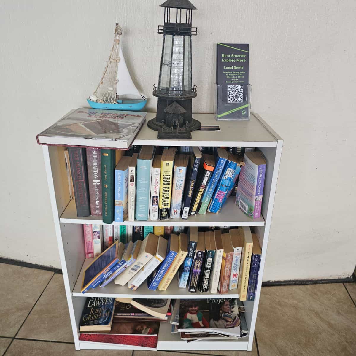 bookshelves with books, lighthouse and sailboat on top of the bookshelf