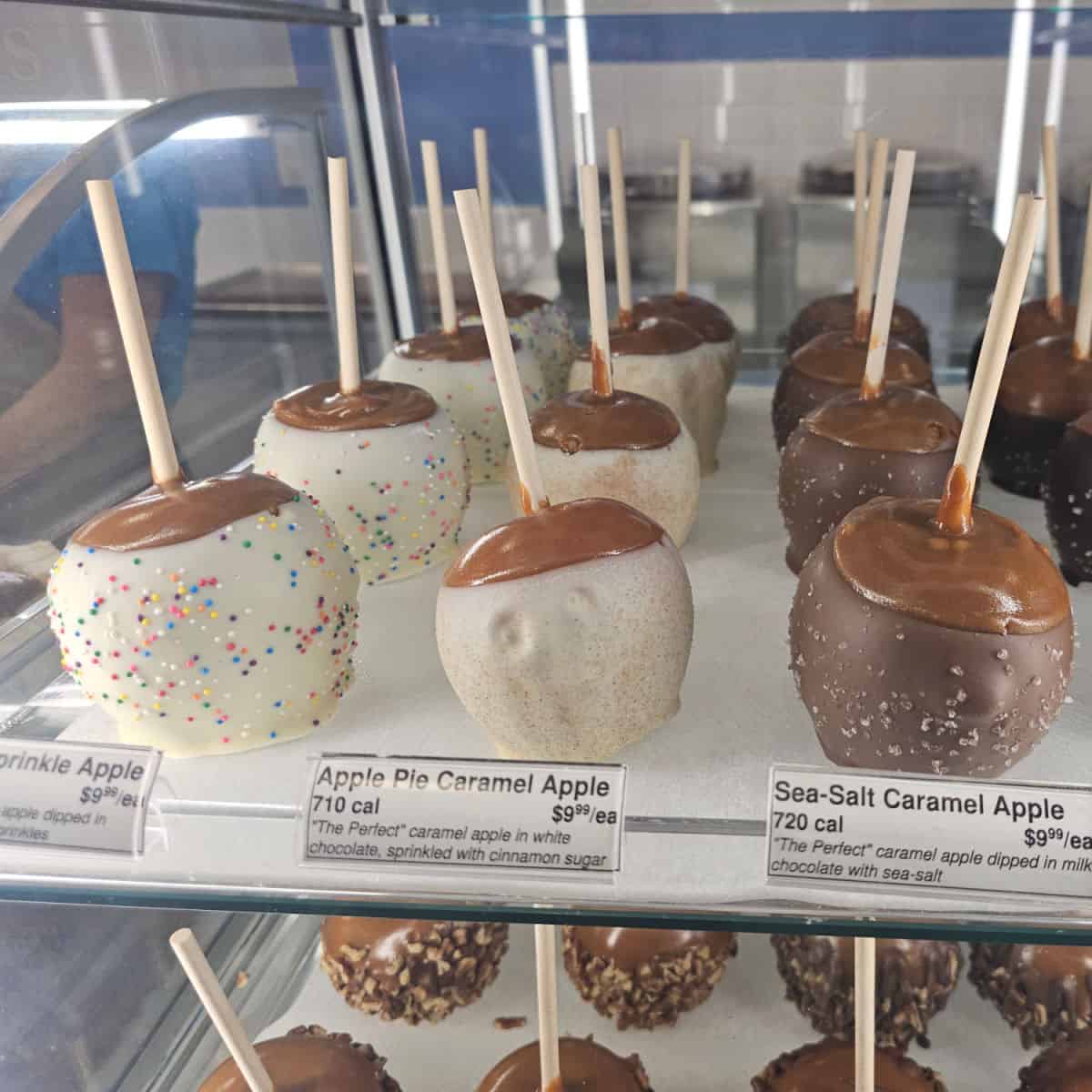 different caramel apples on white shelf in a cabinet