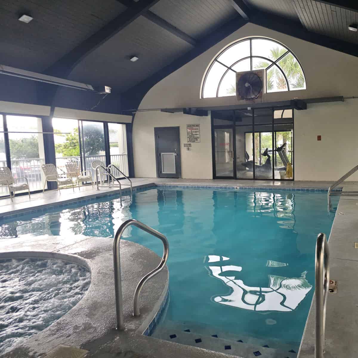 indoor pool in a covered building with a fitness center in the background.