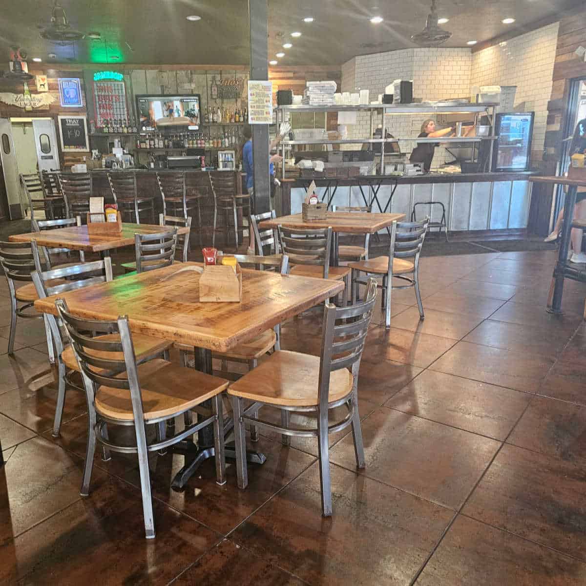 indoor seating area with tables and chairs, open kitchen area preparing orders