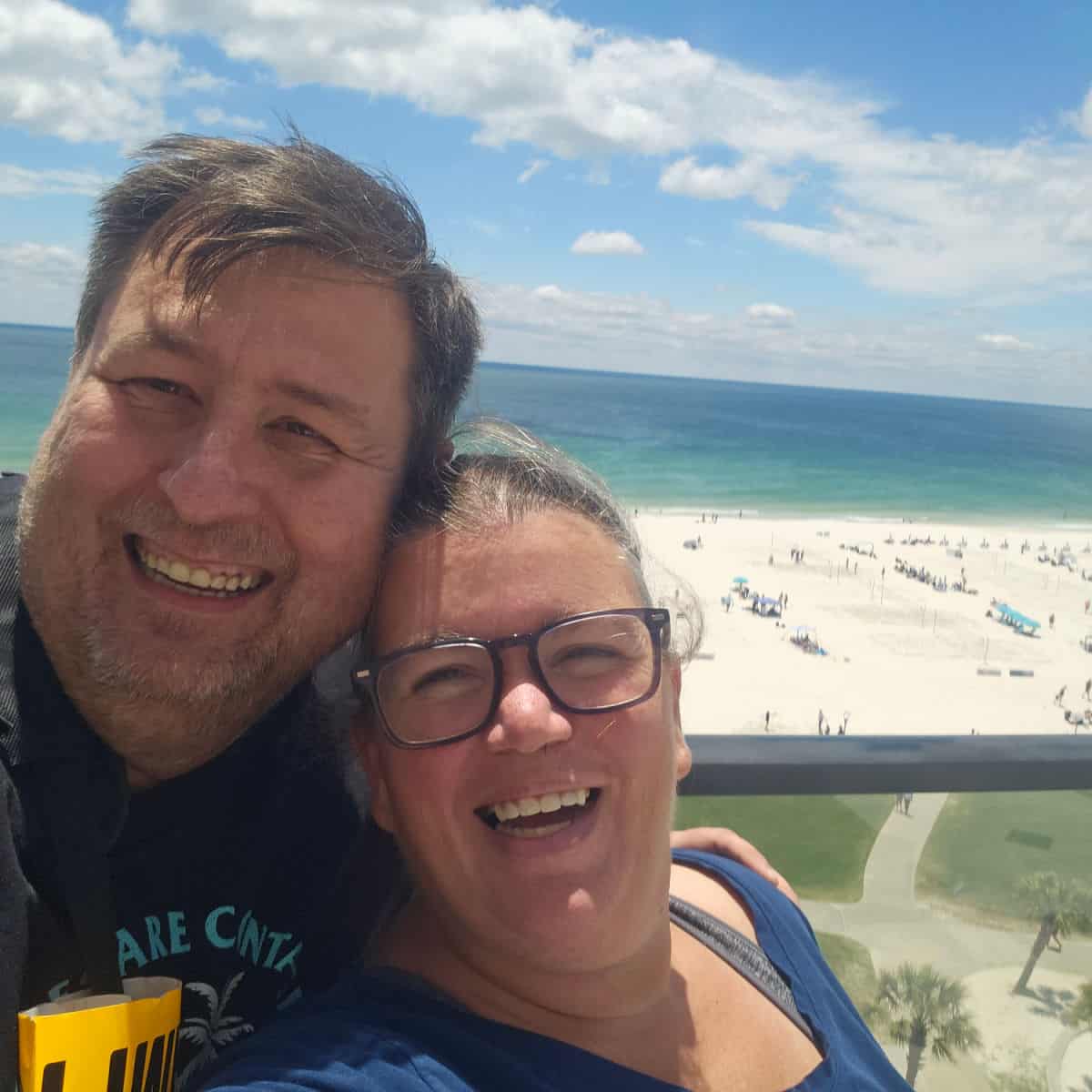 John and tammilee on the rooftop with the Gulf and beach in the background