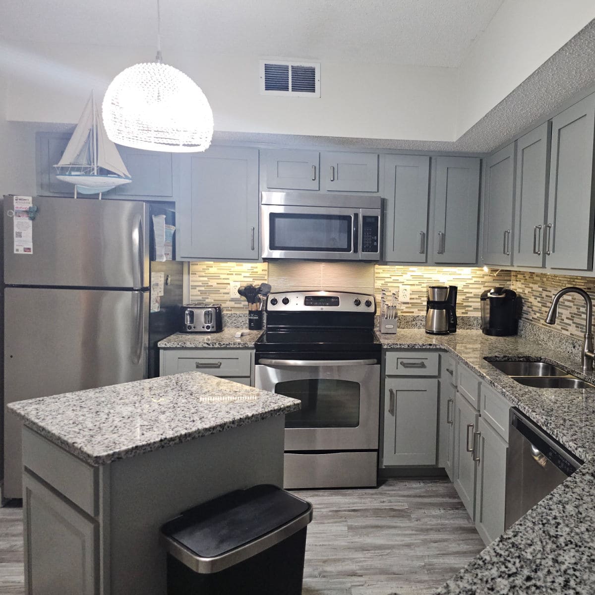 kitchen area with grey cabinets and stainless steel appliances