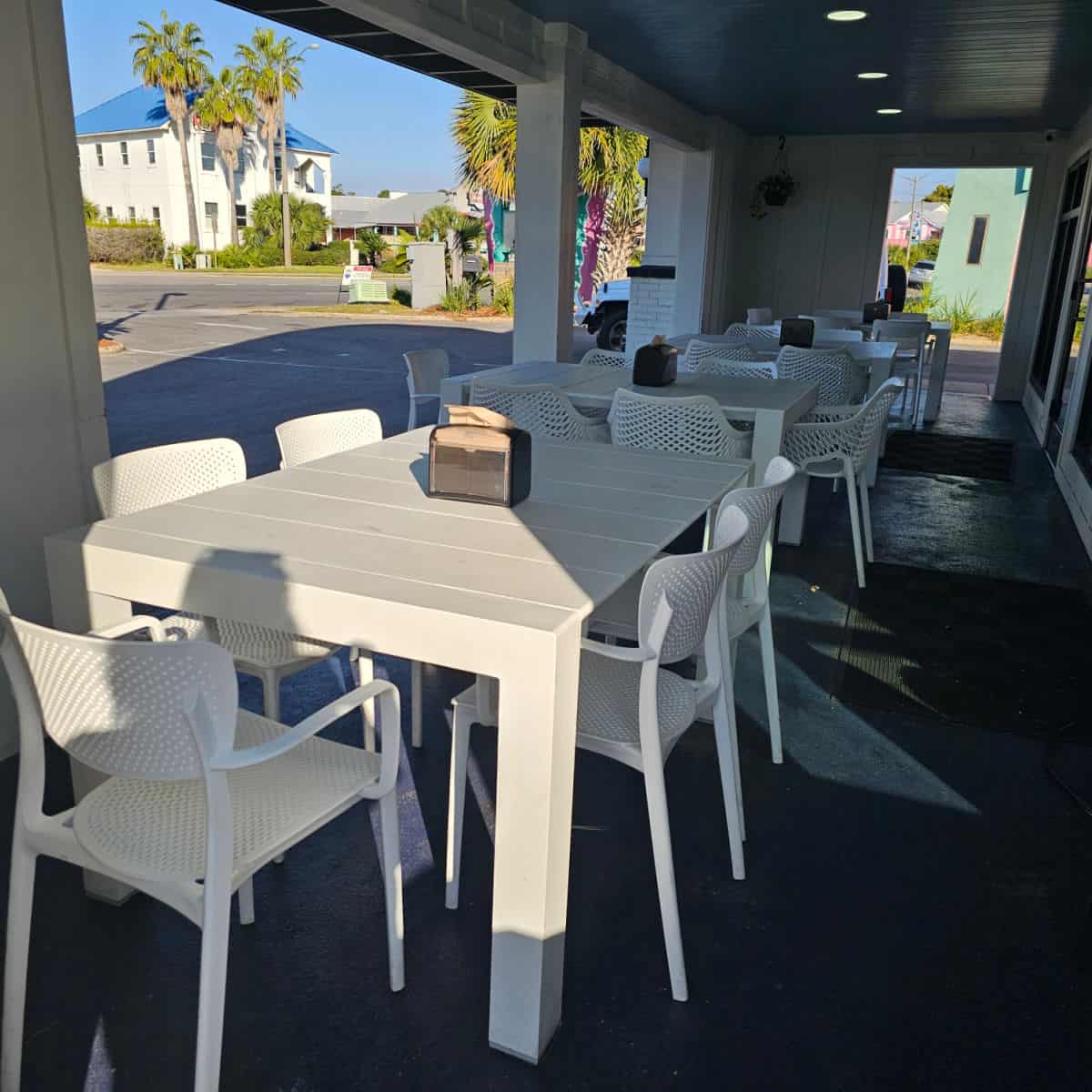 outdoor seating with white tables and chairs under cover