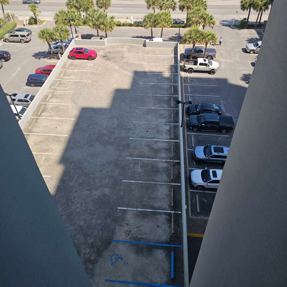 paved parkng area with cars with trees in the background