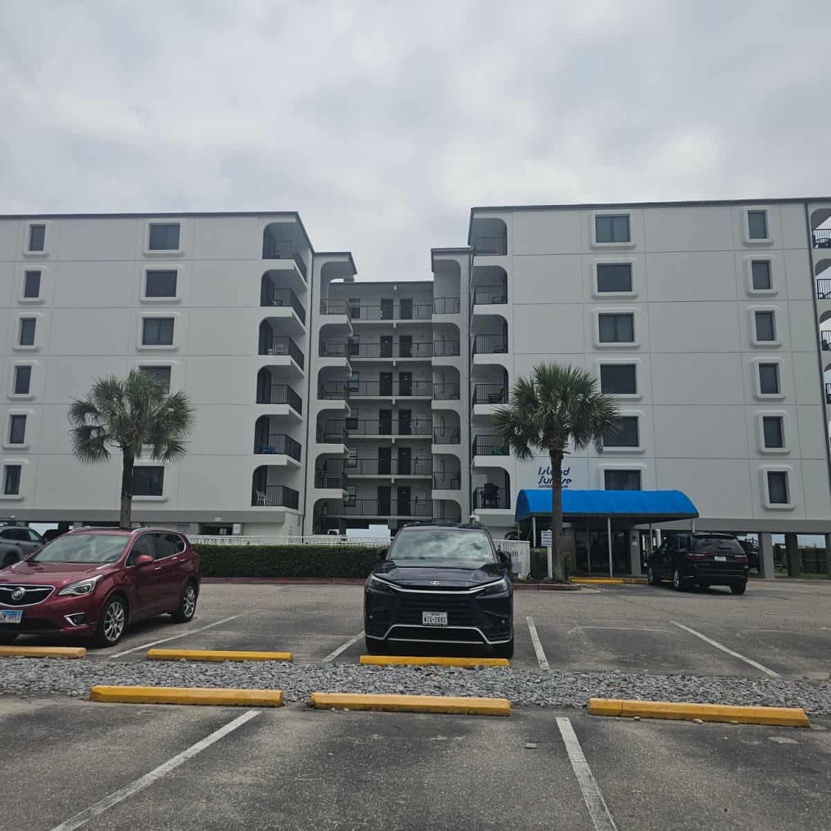 condo building behind the parking area with a few cars