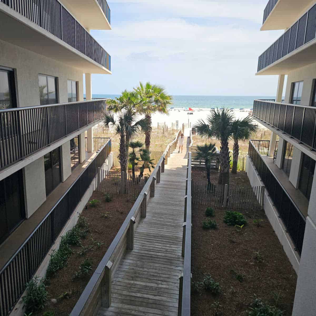 Looking between buildings at a boardwalk leading to the beach