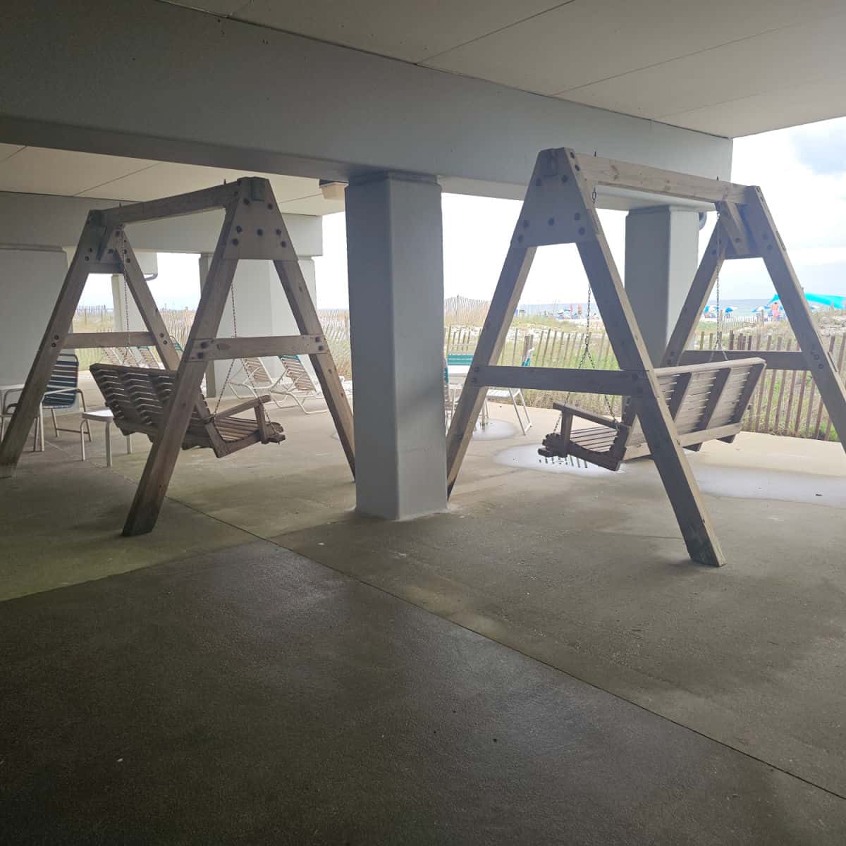 wooden swings under the building, beach in the distance